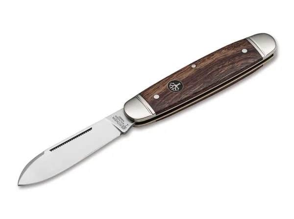 Nóż Böker Club Knife Gentleman Das traditionelle Böker Club Knife ist der elegante Bruder des berühmten Böker Sportmessers, das in Nordamerika als Camp Knife bekannt ist. Bei fast gleichen Abmessungen ist die Formgebung allerdings durchgehend und wird nicht durch Aussparungen für die Werkzeuge unterbrochen. Der charakteristische Metallbügel zur Befestigung einer Messerkette fehlt beim Club Knife ebenfalls. Der Erl der Neuauflage dieses historischen Gentlemanmessers besteht aus Messing, während die dekorativen Backen aus Neusilber gefertigt werden und mit einer fein gefrästen Nut verziert sind. Für die Griffschalen wird reizvoll gemasertes Wüsteneisenholz aus zertifiziertem Import verwendet. Die Klinge mit historischer Formgebung wird aus N690 gefertigt und verriegelt nicht. Der lange Nagelhau, auch Long Pull genannt, ist mit einer feinen Zahnung versehen und erlaubt so das Entzünden von geeigneten Streichhölzern. Die Auslieferung des komplett von Hand in der Böker Manufaktur Solingen gefertigten Slipjoint-Messers erfolgt mit dem neu aufgelegten historischen Böker Baumzeichen-Emblem.