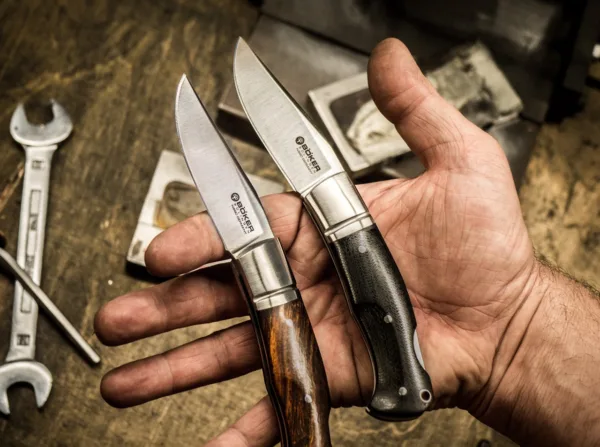 Nóż Böker Boxer Micarta Raphaël Durand aus Thiers ist als Custom-Messermacher inzwischen einer der gefragtesten in Frankreich. Seine handgearbeiteten Stücke erzielen international Höchstpreise, und sein Auftragsbuch ist mehr als voll. Umso mehr freuen wir uns, nach dem Slack von Böker Plus nun aus unserer Solinger Manufaktur eines seiner gefragtesten Modelle anbieten zu können, das Boxer. Der klassische Backlock vereint mediterrane Einflüsse bei der Klingenform mit denen eines traditionellen Taschenmessers und stellt so eine reizvolle Kombination dar, die eine einzigartige Ausstrahlung besitzt. Die Klinge wird aus N690 gefertigt und ist mit einem feinen Satin-Finish versehen. Die Edelstahlbacken tragen die für Raphaël Durand typische Nut. Die Beschalung besteht aus griffigem und stabilem Canvas-Micarta, das hier mit einem schönen gebürsteten Finish versehen ist. Die handliche Größe ist der perfekte Kompromiss zwischen Taschentauglichkeit und Vielseitigkeit im Einsatz, sodass das Boxer ein echter Allrounder ist, der die Freunde besonderer Taschenmesser ganz sicher begeistern wird.