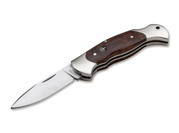 Nóż Böker Scout Spearpoint Desert Ironwood Das Böker Scout ist seit 1985 fest mit unserem Namen verbunden. Das klassische Taschenmesser mit Backlock-Verriegelung ist in all den Jahren immer ein fester Bestandteil unseres Sortiments gewesen und wurde bereits in zahlreichen Varianten gefertigt. Die Aufgabenstellung an unsere Designer und Ingenieure lautete dieses Mal eine neue Klinge für das Scout zu entwickeln und gleichzeitig die elegante Linienführung der Ikone zu erhalten. Die vollkommen neu konzipierte Spearpoint-Klinge mit eleganter Fehlschärfe auf dem Klingenrücken erfüllt dieses Anforderungsprofil perfekt. Das Scout wirkt nun moderner und dynamischer, ohne im Auftritt aufdringlich oder gar aggressiv zu sein. Für das erste Modell in dieser Ausführung haben wir matt poliertes, zertifiziert importiertes Wüsteneisenholz als Beschalungsmaterial gewählt, das hervorragend mit dem ergonomisch geformten Griffkörper aus gesintertem Neusilber harmoniert. Die Klinge wird aus stickstofflegiertem N690 gefertigt und ist flach geschliffen.