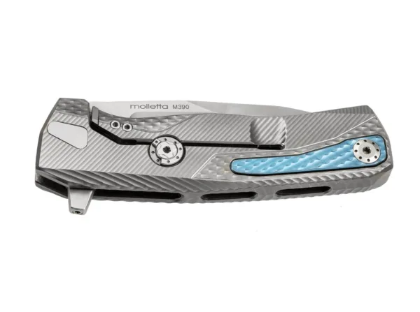 Nóż LionSteel ROK Titan Grey ROK to nowy hit LionSteel wśród noży monoblokowych, charakteryzujący się rękojeścią wyfrezowaną z jednego litego bloku. Misternie wyfrezowana tekstura 3D zapewnia doskonały chwyt i fascynujący wygląd. Innowacyjnym szczegółem jest wysuwany klips. Cechą szczególną jest wpuszczony w rękojeść klips, który można łatwo wysunąć tak, aby w żaden sposób nie utrudniał użytkowania noża. Ostrze posiada również wyjmowany flipper, który umożliwia noszenie noża w jednej lub obu dłoniach. Framelock jest zabezpieczony wypróbowanym i przetestowanym Rotoblockiem. Ostrze to stal proszkowa Böhler M390. Z szarą tytanową rękojeścią i tytanowym klipsem.