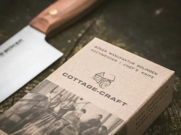 Nóż Santoku Böker Solingen Cottage-Craft Tak zwani Kotten kształtują historię miasta Solingen od XIV wieku. Masywne osełki napędzane były czystą wodą, a słynne na całym świecie ostrza szlifowano ręcznie. Seria noży szefa kuchni Böker Cottage-Craft imponująco kontynuuje dziedzictwo tego tradycyjnego rzemiosła i zachwyca starannie dobranym wyborem klasycznych materiałów. Na szczególną uwagę zasługuje zastosowanie rdzewnej stali węglowej C75, która po krótkim okresie użytkowania tworzy typową niebiesko-szarą patynę. Naturalne drewno śliwkowe użyte do wykonania muszli rękojeści jest twarde, gęste i drobnoporowate, ma jednolitą strukturę i uderzające spektrum kolorów. Zgodnie z wielowiekową tradycją produkcji noży z Solingen, łuski rękojeści są mocowane na ciągłym trzpieniu ostrza za pomocą nitów z litego mosiądzu.Nóż, który staje się coraz bardziej popularny w Europie, to Santoku. Pierwotnie był to japoński kształt ostrza noża użytkowego. W tłumaczeniu jego nazwa oznacza „Trzy cnoty” i nadaje się równie dobrze do mięsa, ryb i warzyw. Dzięki szerokiemu ostrzu Santoku jest szczególnie łatwy w obsłudze.CARBON STEEL C75 Całkowicie naturalną właściwością materiału jest to, że podczas używania noża powstaje patyna. Szaroniebieskie zmatowienie ostrza jest całkowicie normalne i nie jest w żaden sposób wadą. Wręcz przeciwnie, powstała w ten sposób patyna (warstwa tlenku) tworzy na ostrzu warstwę ochronną, która zwiększa jego odporność na warunki zewnętrzne. Ta patyna jest często widoczna już po pierwszym użyciu i nie można jej ponownie usunąć. Ekspert natychmiast rozpoznaje wynikającą z tego wysokiej jakości stal węglową. Przy odpowiedniej pielęgnacji stal węglowa ma taką samą żywotność jak nowoczesna stal nierdzewna. CZYSZCZENIE I PIELĘGNACJA Stal węglowa jest jednym z rdzewnych rodzajów stali i wymaga celowej, ale minimalnej konserwacji. W kuchni wystarczy opłukać nóż pod gorącą bieżącą wodą i osuszyć ściereczką. W przypadku dłuższego przechowywania ostrze należy konserwować odpowiednim olejem. Idealny do tego celu jest bezkwasowy, nieżywiczny i nielotny olej Boker Camellia (nr kat. 04BO175). Jest olejem czysto roślinnym i idealnie nadaje się do konserwacji rdzewnych noży kuchennych, w przeciwieństwie do innych olejów pielęgnacyjnych – nie tworzy emulsji z wodą. Z drugiej strony, używanie zmywarki niszczy drobne struktury stali węglowej, podobnie jak pozostawianie ostrza w zlewie na dłuższy czas bez czyszczenia. Rzadko stosowana w nożach kuchennych stal węglowa, ze względu na swoje właściwości można ją łatwo ostrzyć, dzięki czemu noże Boker Cottage Craft stają się lojalnymi i niezawodnymi towarzyszami na całe życie i kontynuują pisanie własnej historii.