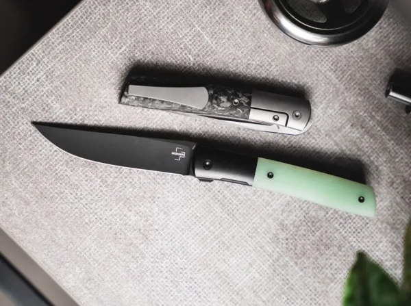 Nóż Böker Plus Urban Trapper Premium G10 Jade Boker Plus Urban Trapper zaprojektowany przez Brada Zinkera przekonuje w tej nowoczesnej wersji premium dostarczanej z ostrzem łożyska kulkowego wykonanym z metalurgii proszków M390 i dyskretnym przednim flipperem. Powlekana na czarno stal o wysokiej wydajności firmy Böhler wykazuje maksymalną odporność na zużycie i bez wysiłku radzi sobie ze wszystkimi codziennymi zadaniami cięcia. Ostrze jest unieruchomione solidną ramą z wkładką ze stali nierdzewnej. Wyżłobienia w okolicy oparcia kciuka dodatkowo zwiększają bezpieczeństwo pracy. Urban Trapper Premium ma integralną konstrukcję z wytrzymałym korpusem rękojeści wykonanym z czarnego powlekanego tytanu, który jest wyfrezowany z litego materiału i stanowi również wyprofilowane podpory dżentelmeńskiego noża. Powstałą lekkość stopy podkreślają podobnie wyprofilowane łuski uchwytów wykonane z Natural Jade G10, półprzezroczystej oryginalnej odmiany wytrzymałego materiału kompozytowego. Dostarczany z frezowanym klipsem z tytanu (czubkiem do góry/p) i wysokiej jakości nylonowym etui do przechowywania.