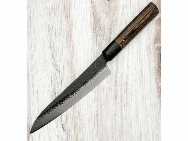 Shizu Hamono GEN Japoński nóż Gyuto 18cm VG-10 Shizu Hamono szczyci się wytwarzaniem noży, które bezbłędnie łączą estetykę z niezwykłą funkcjonalnością, wybitny podmiot w dziedzinie tradycyjnej ręcznie wykonanej sztuki wytwarzania z wykorzystaniem uświęconej tradycją techniki i stosowania najwyższej jakości materiałów Dane techniczne: Rękojeść: D Shape Pakkawood Stal: Damast VG10 Twardość / HRC: 60/62 Waga: 142 g Długość ostrza: 183 mm Długość całkowita: 323 mm Grubość grzbietu u podstawy: 2,2 mm Wysokość ostrza: 38,6 mm Wyprodukowano w Japonii Gyuto - nóż, który idealnie nadaje się do krojenia mięsa, drobiu, siekania warzyw i owoców, a także delikatnego filetowania ryb. Dzięki niemu unikniesz problemu odrapanych kawałków, które mogą zniszczyć Twoje kulinarne arcydzieła. Shizu Hamono wyróżnia się japońską stalą najwyższej jakości oraz wygodnym uchwytem, który zapewnia komfort podczas pracy. Gwarantujemy, że po doświadczeniu pracy z tym nożem, już nigdy nie będziesz chciał wrócić do innych narzędzi kuchennych. Wybierz Gyuto i poczuj różnicę, jaką może zrobić doskonały nóż w Twojej kuchni.