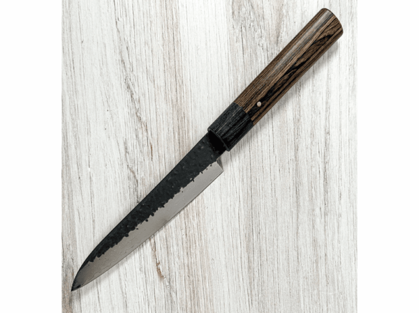 Shizu Hamono GEN Japoński nóż Gyuto 18cm VG-10 Shizu Hamono szczyci się wytwarzaniem noży, które bezbłędnie łączą estetykę z niezwykłą funkcjonalnością, wybitny podmiot w dziedzinie tradycyjnej ręcznie wykonanej sztuki wytwarzania z wykorzystaniem uświęconej tradycją techniki i stosowania najwyższej jakości materiałów Dane techniczne: Rękojeść: D Shape Pakkawood Stal: Damast VG10 Twardość / HRC: 60/62 Waga: 142 g Długość ostrza: 183 mm Długość całkowita: 323 mm Grubość grzbietu u podstawy: 2,2 mm Wysokość ostrza: 38,6 mm Wyprodukowano w Japonii Gyuto - nóż, który idealnie nadaje się do krojenia mięsa, drobiu, siekania warzyw i owoców, a także delikatnego filetowania ryb. Dzięki niemu unikniesz problemu odrapanych kawałków, które mogą zniszczyć Twoje kulinarne arcydzieła. Shizu Hamono wyróżnia się japońską stalą najwyższej jakości oraz wygodnym uchwytem, który zapewnia komfort podczas pracy. Gwarantujemy, że po doświadczeniu pracy z tym nożem, już nigdy nie będziesz chciał wrócić do innych narzędzi kuchennych. Wybierz Gyuto i poczuj różnicę, jaką może zrobić doskonały nóż w Twojej kuchni.