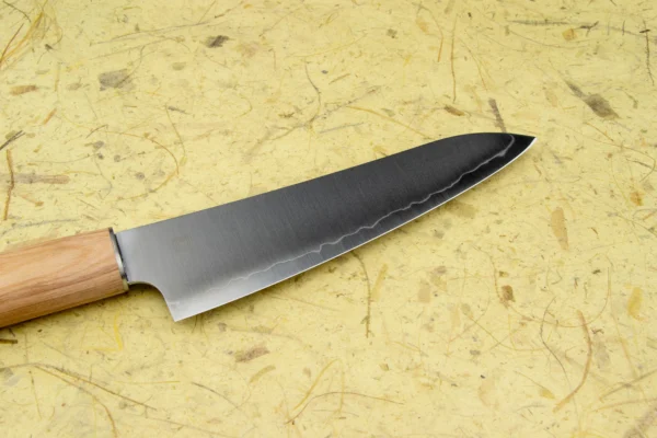 Shizu Hamono Yuri Japoński nóż uniwersalny Petty 14cm AUS-8 Doświadcz niezrównanej elegancji i funkcjonalności z nożem SHIZU HAMONO Yuri Petty 140mm, wyprodukowanym przez renomowaną firmę Shizu Hamono Co. w Seki, Gifu, Japonia. Petty to wszechstronny nóż, idealny do precyzyjnych cięć i drobnych prac kuchennych. Specyfikacje Techniczne Ostrze : AUS-8 Rękojeść: Oval Pakka wood Długość całkowita 250 mm Długość ostrza 140 mm Waga 65g Wyprodukowano w Seki City, Japonia   Doświadcz elegancji, funkcjonalności i niezawodności, jakie oferuje nóż Shizu Hamono spraw, aby przygotowywanie posiłków było sztuką przyjemności